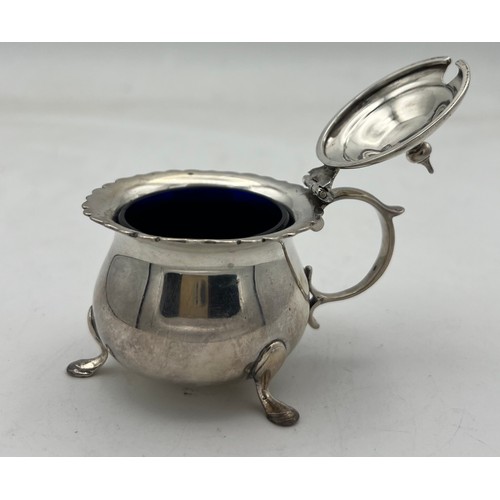 67 - A lidded silver mustard pot raised on three hoof feet and blue glass liner, Chester 1904. Maker Geor... 