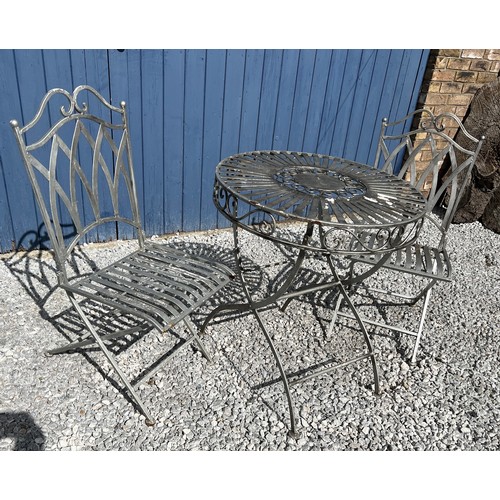 95C - A silvered cast steel garden table and two chairs. Table 75cm h x 68cm diameter.