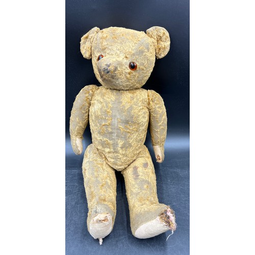 1066 - An early 20th century well loved straw filled teddy bear. Approximately 51cm high.