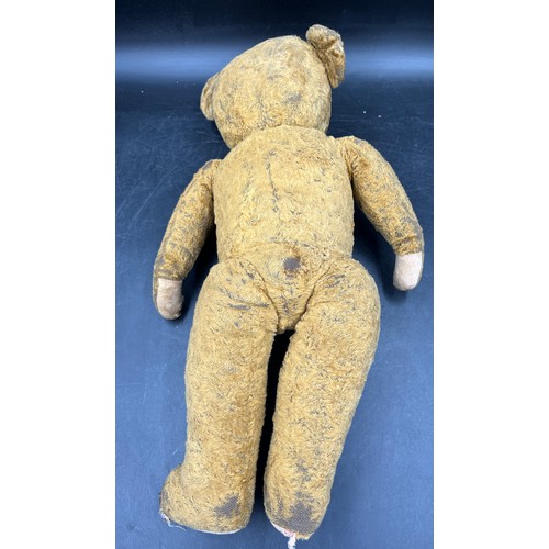 1066 - An early 20th century well loved straw filled teddy bear. Approximately 51cm high.