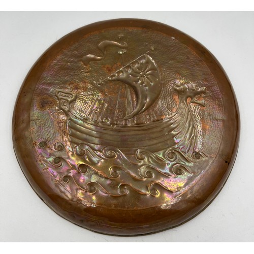 1179 - Keswick school copper wall plate by W.H Mawson embossed with a Viking ship, 20.5cm d,