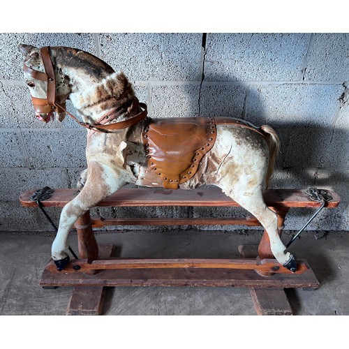 1102 - An early 20thC skin covered wooden rocking horse with leather saddle and bridle. Horse hair tail. 11... 