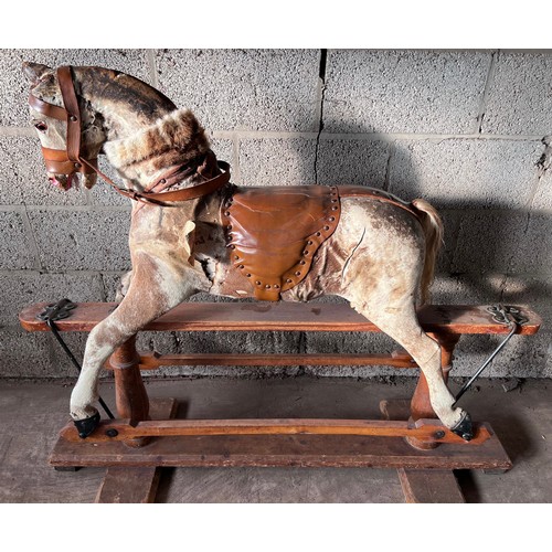 1102 - An early 20thC skin covered wooden rocking horse with leather saddle and bridle. Horse hair tail. 11... 