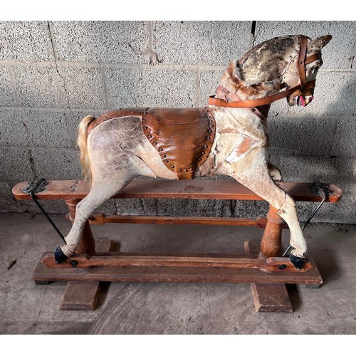 1102 - An early 20thC skin covered wooden rocking horse with leather saddle and bridle. Horse hair tail. 11... 