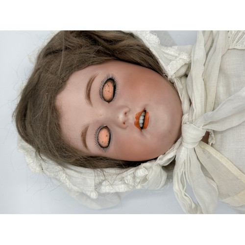 1074 - A German porcelain head doll by Simon & Halbig. Marked S & H 10 with blue sleeping eyes, light brown... 