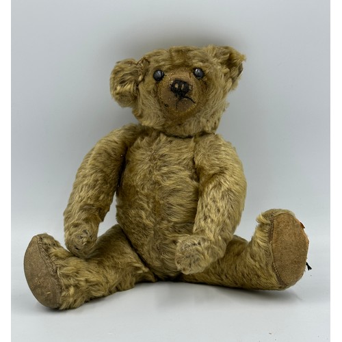 1076 - An early 20thC straw filled Teddy with button eyes and long snout and paws. Approx. 33cm long.