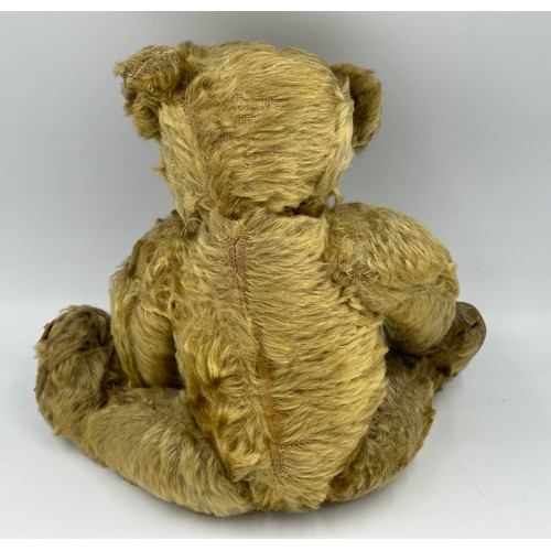 1076 - An early 20thC straw filled Teddy with button eyes and long snout and paws. Approx. 33cm long.