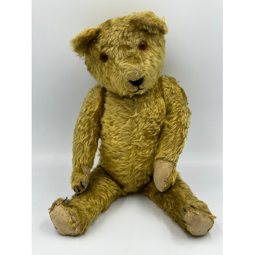 1077 - An early 20thC straw filled Teddy with glass amber eyes black stitched nose, mouth and claws, swivel... 