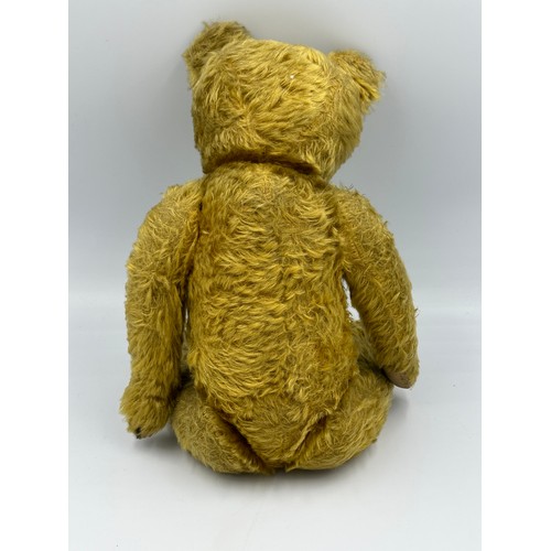 1077 - An early 20thC straw filled Teddy with glass amber eyes black stitched nose, mouth and claws, swivel... 