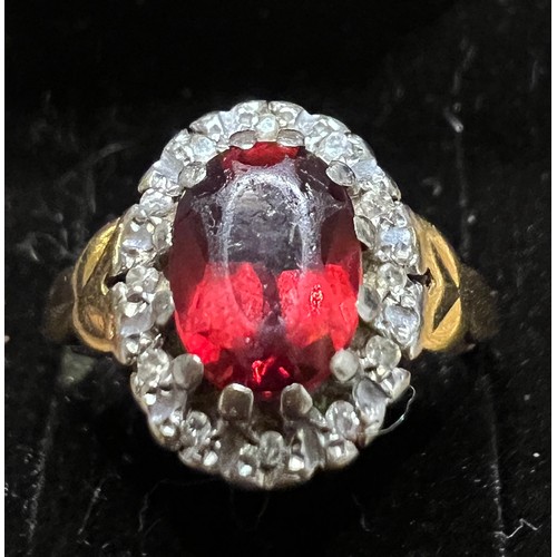 411 - An 18 carat gold ring set with red stone surrounded by diamonds. Size M. Weight 4.2gm.