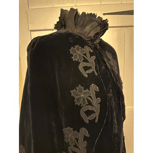 938 - A Victorian black velvet cape with stand up taffeta collar and applied decoration. Back of neck to h... 