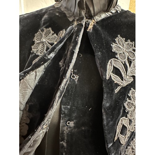 938 - A Victorian black velvet cape with stand up taffeta collar and applied decoration. Back of neck to h... 