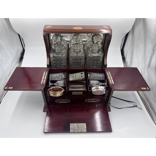 1274A - An Edwardian mahogany inlaid cut glass tantalus and games box containing cigar cutter, silver plated... 