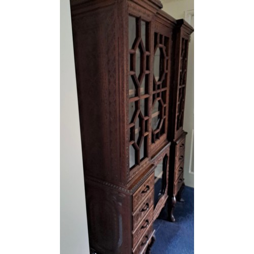 69 - A very highly carved hardwood display cabinet/ bookcase, three glazed doors over a base of drawers a... 