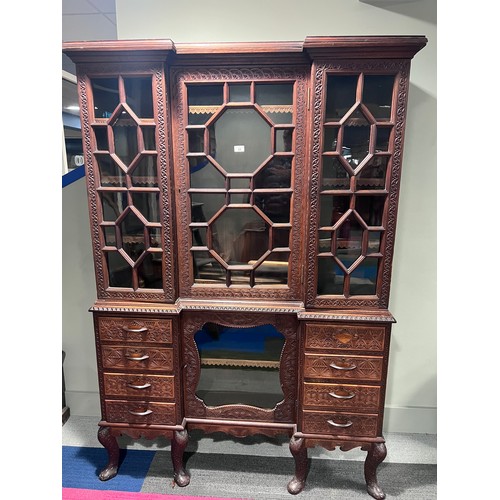 69 - A very highly carved hardwood display cabinet/ bookcase, three glazed doors over a base of drawers a... 