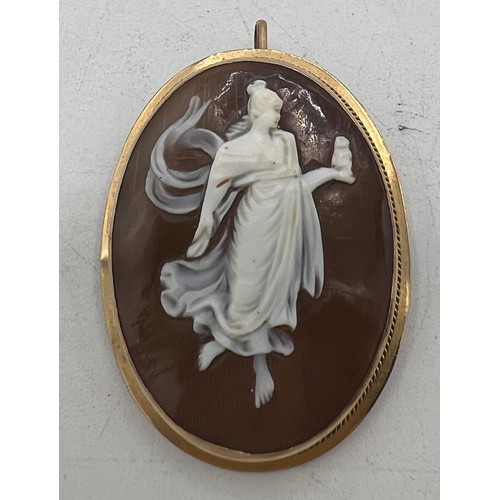 448 - A carved shell cameo locket/brooch mounted in unmarked yellow metal. Size 4cm x 3cm.