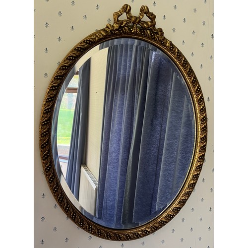 1015 - A gilt framed bevel edged oval wall mirror. 58cm x 44cm.