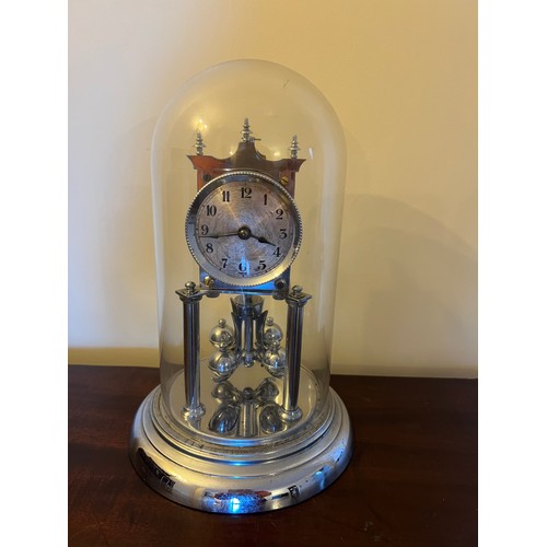 1007 - A chrome anniversary clock under a glass dome, complete with key. 30cm h.