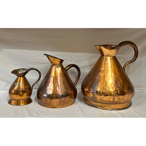 909 - A collection of three large antique copper jugs: 4 gallon, 2 gallon and half gallon approx. 43cm h.