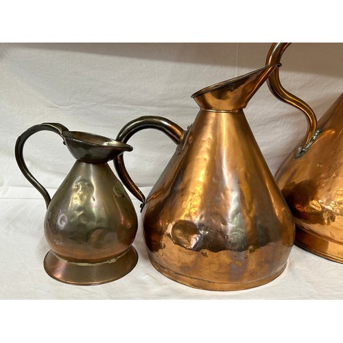 909 - A collection of three large antique copper jugs: 4 gallon, 2 gallon and half gallon approx. 43cm h.