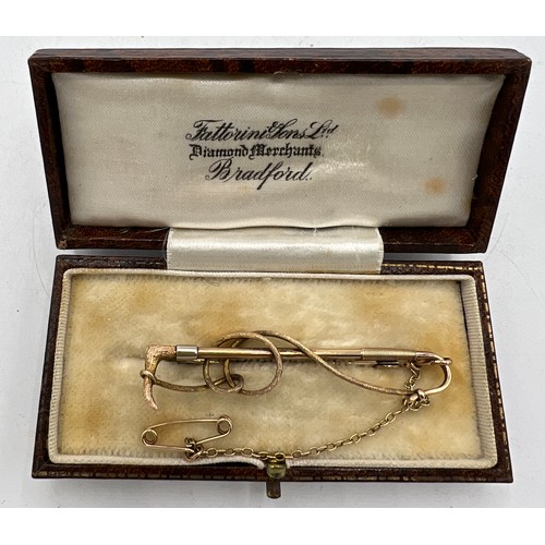 475 - A nine carat gold bar brooch in the form of a riding crop with safety chain, in fitted presentation ... 