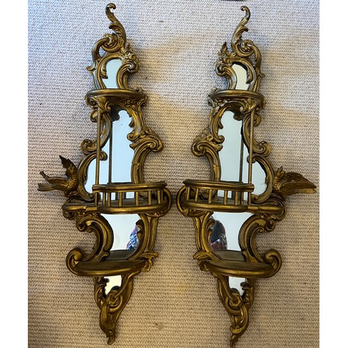 1019 - A pair of 19thC decorative wooden gilt wall mirrors with galleried shelves with bird and floral deco... 