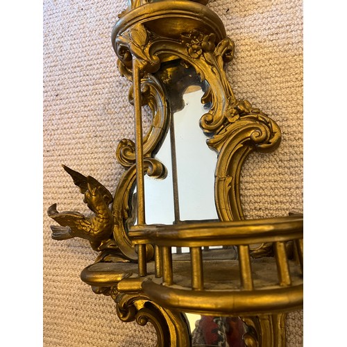 1019 - A pair of 19thC decorative wooden gilt wall mirrors with galleried shelves with bird and floral deco... 