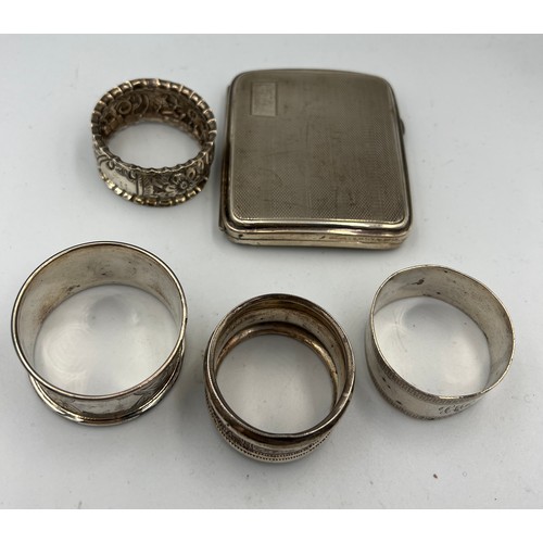 733 - Four silver napkin rings and a silver cigarette case. Various dates and makers. Total weight 158gm.