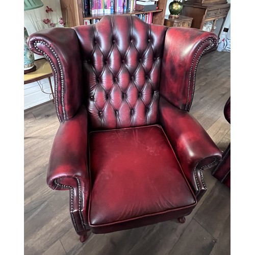 112 - A red leather suite comprising three seater Chesterfield together with wing armchair and low backed ... 