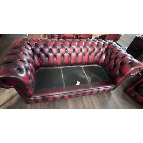 112 - A red leather suite comprising three seater Chesterfield together with wing armchair and low backed ... 