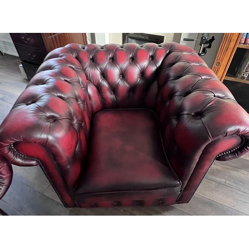 112 - A red leather suite comprising three seater Chesterfield together with wing armchair and low backed ... 