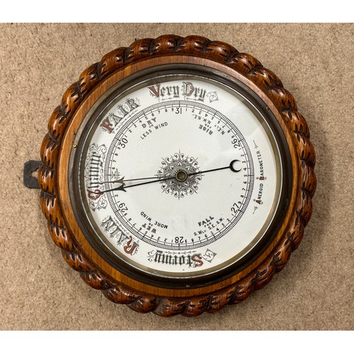 1008 - An oak cased aneroid barometer circa 1920's with a ceramic dial, a rope twist design carved case and... 