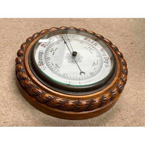 1008 - An oak cased aneroid barometer circa 1920's with a ceramic dial, a rope twist design carved case and... 