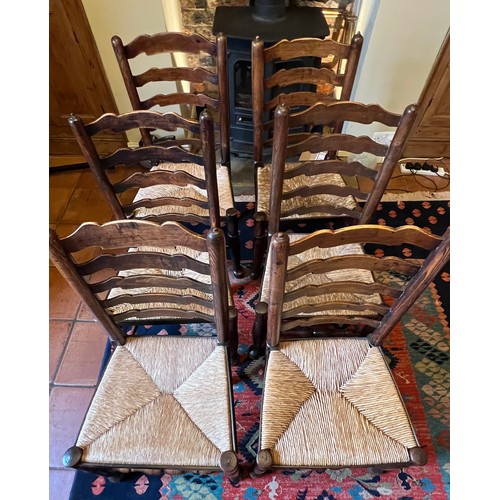 43 - Eight oak ladder back dining chairs with rush seats to include two carvers.