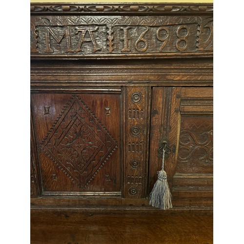 45 - An oak court cupboard with carving to the top, MA 1698. 138cm w x 57cm d x 151cm h.
Top shows signif... 