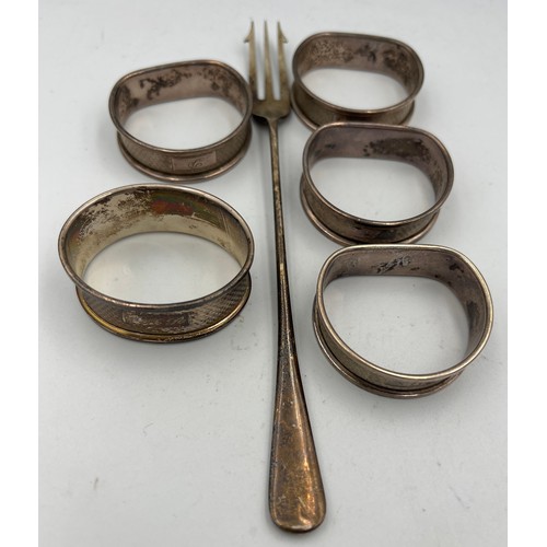 664 - Five silver napkin rings and a fork. Total weight 80.1gm.  Various dates and makers.