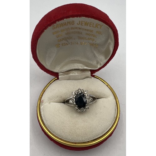 370 - A 14 carat white gold ring set with central sapphire surrounded by diamonds. Size K. Weight 5gm.