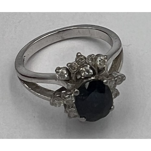 370 - A 14 carat white gold ring set with central sapphire surrounded by diamonds. Size K. Weight 5gm.