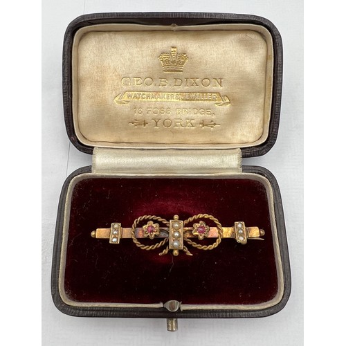 387 - A 15 carat gold bar brooch set with seed pearls and pink stones in original silk and velvet lined pr... 