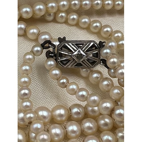 388 - A triple row cultured pearl necklace with 9 carat white gold and diamond clasp. 42cm l. In original ... 