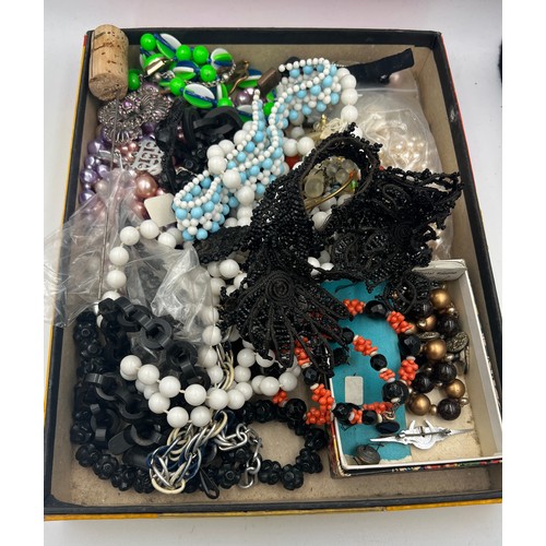 390 - A box of miscellaneous beads, trimmings, brooches, jet etc. Box size 28cm x 22cm x 3.5cm.