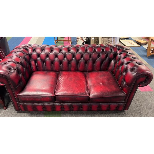 112 - A red leather suite comprising three seater Chesterfield together with wing armchair and low backed ... 