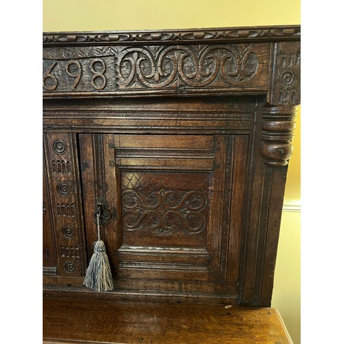 42 - An oak court cupboard with carving to the top, MA 1698. 138cm w x 57cm d x 151cm h.
Top shows signif... 