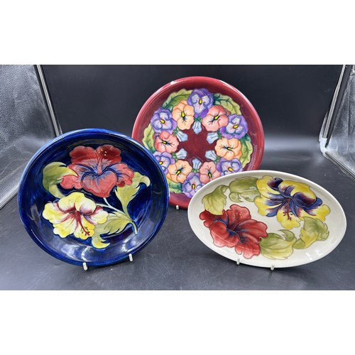 250 - A collection of three Moorcroft plates largest 26cm d in the Pansy pattern, two in the Hibiscus patt... 