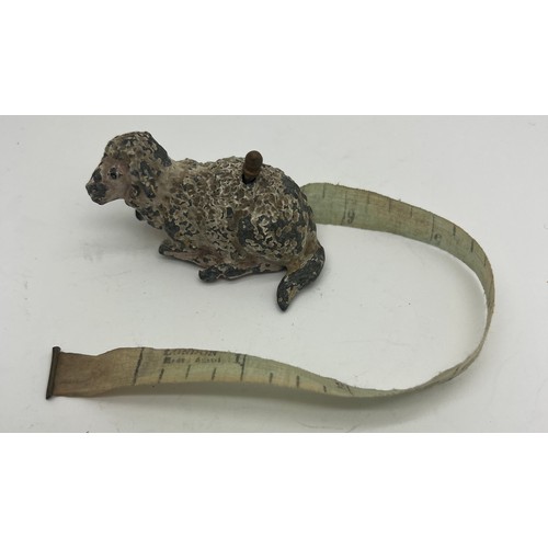 1271 - An early 20thC metal sheep tape measure. 5cm l. Measures centimetres and inches.