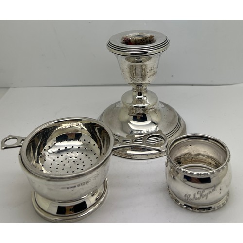 936 - Silver to include tea strainer on bowl, napkin ring and a candlestick with weighted base. Various da... 