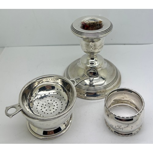 936 - Silver to include tea strainer on bowl, napkin ring and a candlestick with weighted base. Various da... 