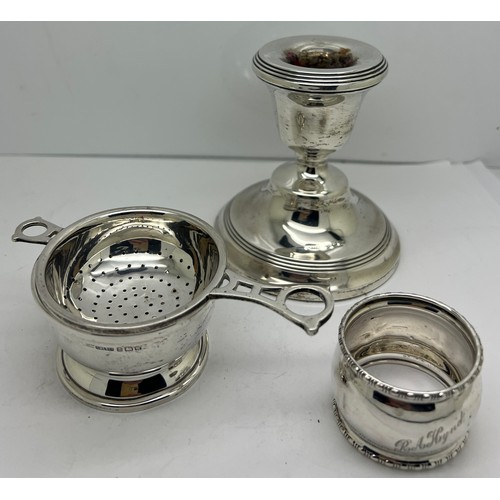 936 - Silver to include tea strainer on bowl, napkin ring and a candlestick with weighted base. Various da... 