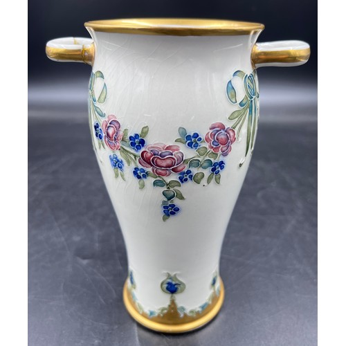 204 - A William Moorcroft for Macintyre Burslem vase with floral garlands and rosettes. 19cms. Stamped to ... 