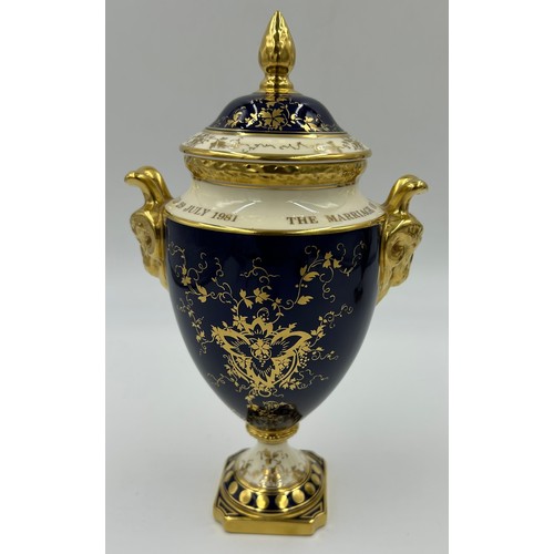 197 - Coalport: Two twin-handled commemorative urn shaped vases with covers and twin goat head handles, on... 